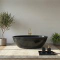 Modern black freestanding bathtub in a minimalistic bathroom with plants and decorative items#color_black